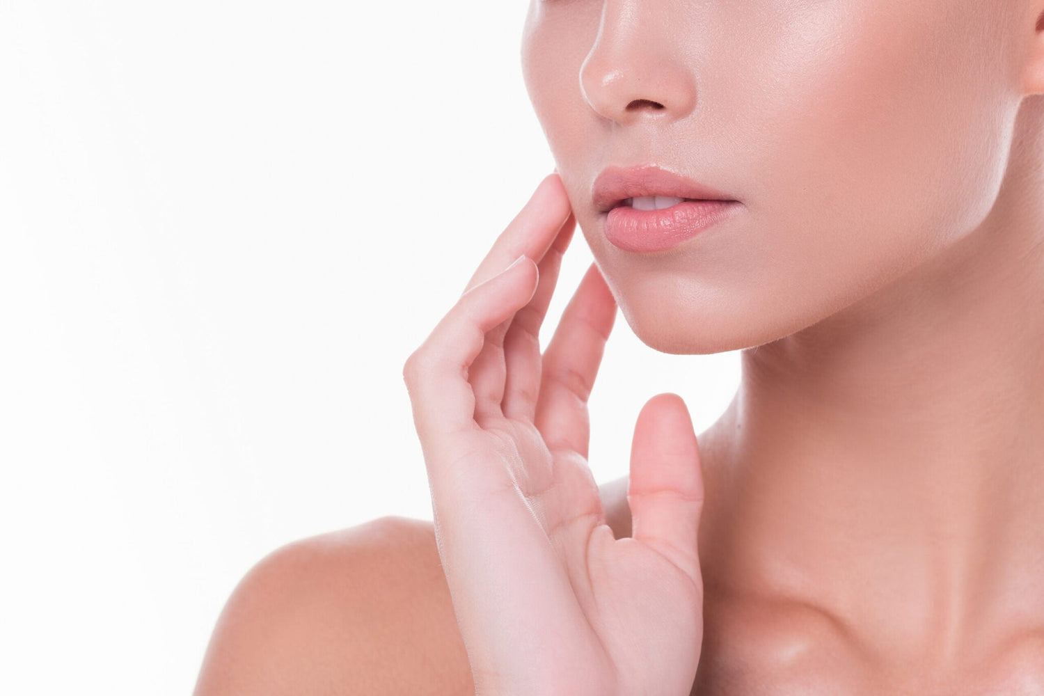 Close-up of half portrait of a beautiful young girl with clear and radiant skin on her face and neck posing on a white background. Concept of proper skin care and salon treatments. Advertising space